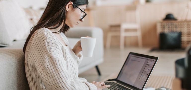 Woman working remotely with coffee and laptop